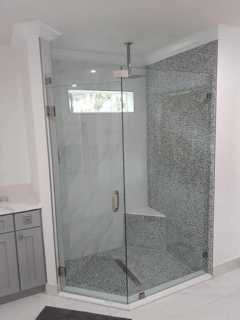 Ducha de vidrio en esquina con azulejos de mosaico