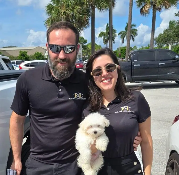 Fabio y Livia, los dueños de F&L, sonriendo con sus camisas polo de F&L y un perrito blanco