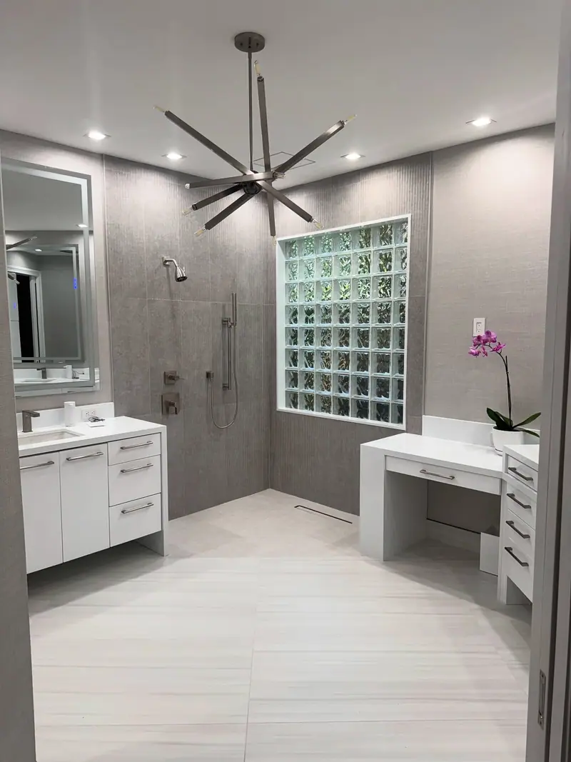Ducha a ras de piso con azulejos grises texturizados y una ventana de bloques de vidrio