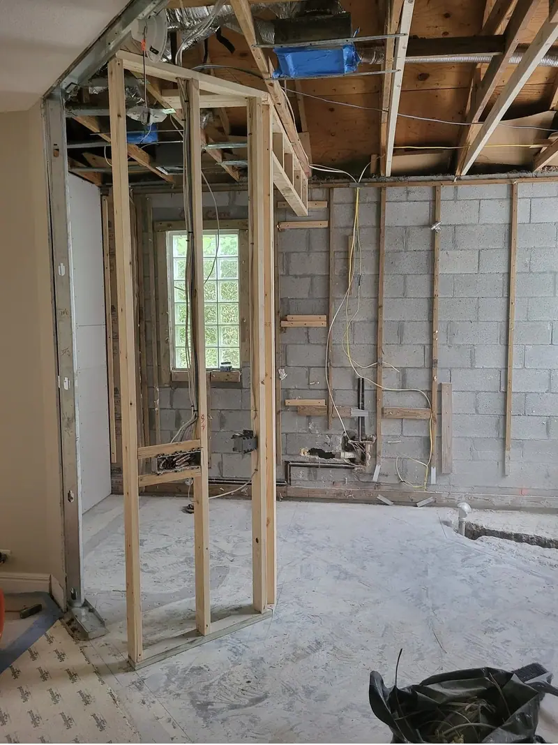 El baño abierto hasta las paredes de bloque, con nueva estructura de madera, las vigas del techo a la vista, cableado y plomería