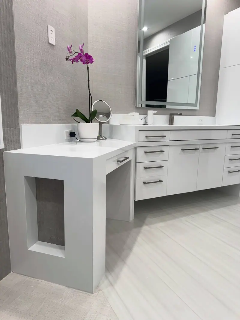 Mesa de maquillaje blanca en cascada con un panel lateral calado, junto al tocador