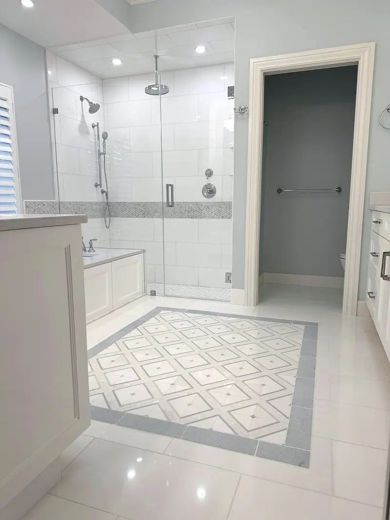 Glass shower beside the tub, with a diamond-pattern floor inlay framed in blue-gray tile and the toilet room door on the right