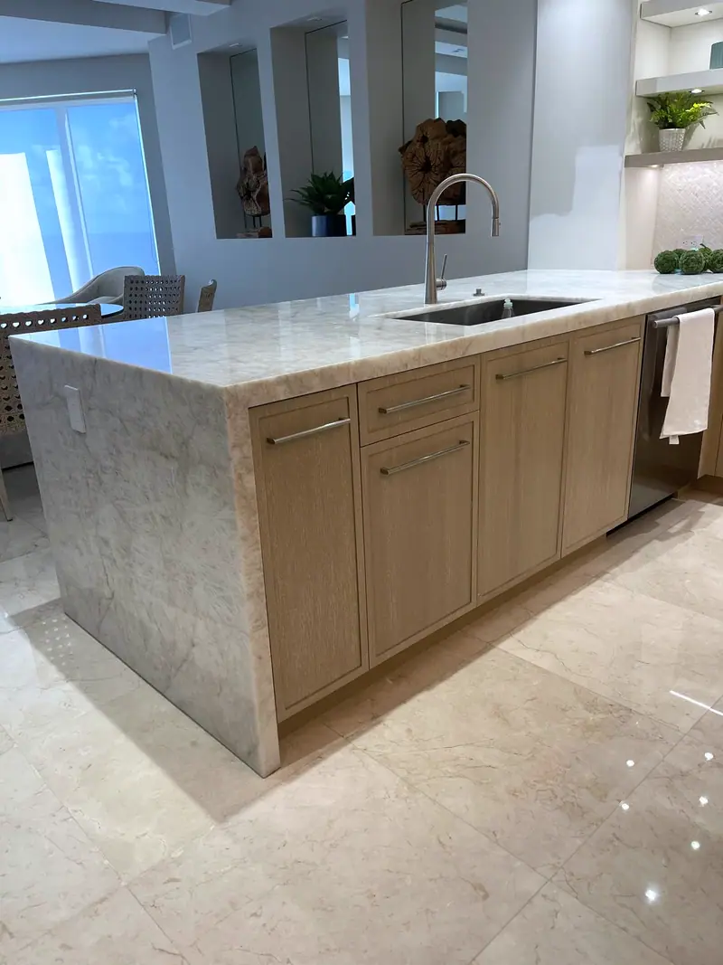 Isla de cocina con encimera de piedra en cascada y gabinetes de roble claro