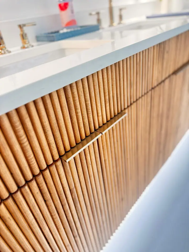 The fluted wood fronts up close, with a brass edge pull and the white counter above